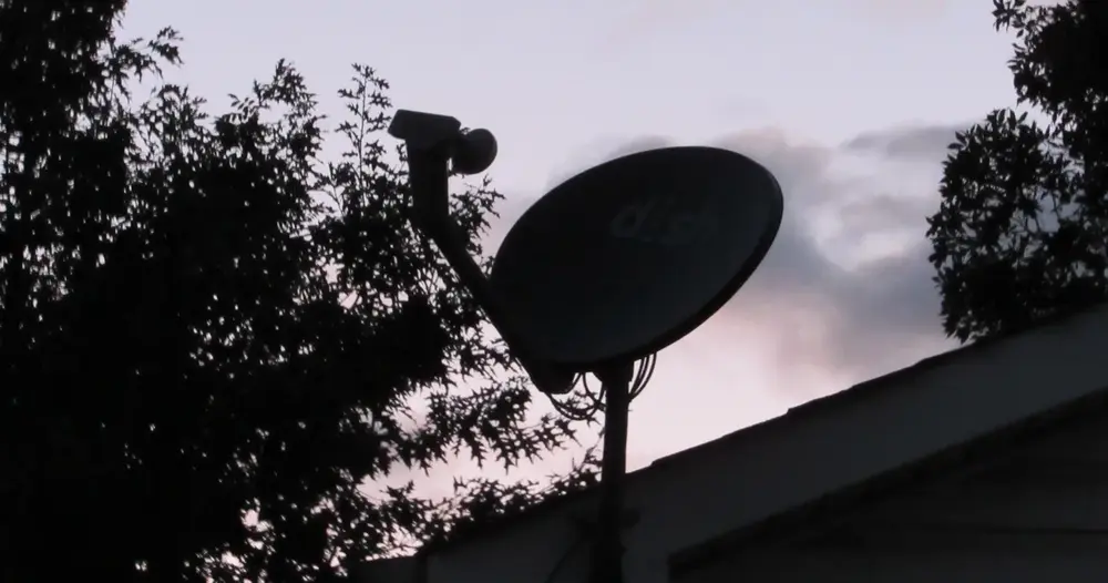 Antena parabólica pequena instalada em telhado ao entardecer